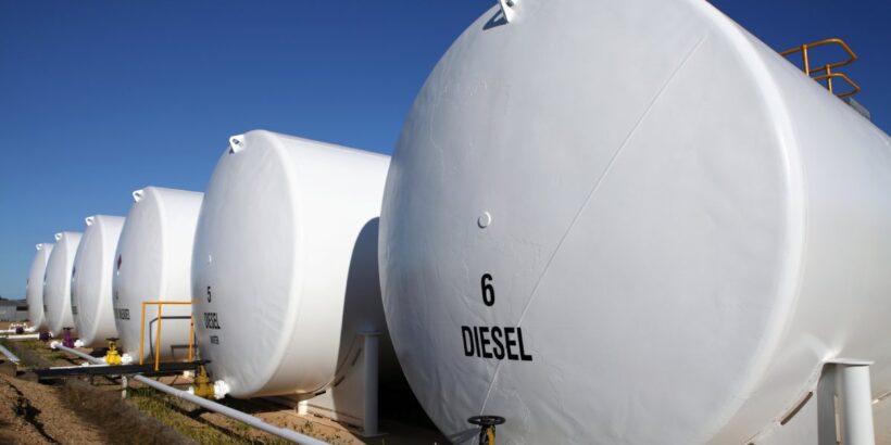 Six white, cylindrical fuel tanks labeled "Diesel" in black letters aligned in a row on a sunny day.