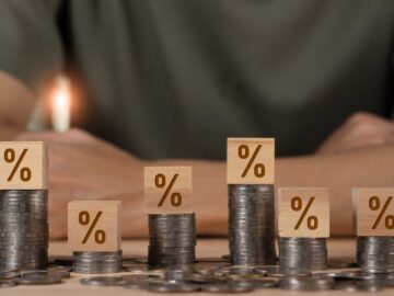 A bunch of coins laid out on a table, with some in tall stacks. The ones in stacks have blocks with percentage signs on them.