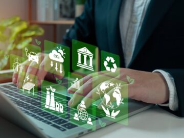 A person types on a laptop, and green icons float above the keyboard. The icons feature a recycle symbol, a globe, and more.